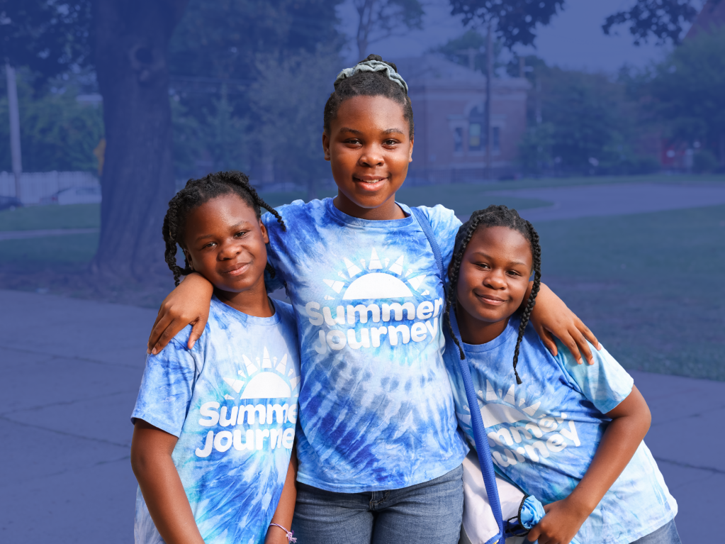 Three students smiling in Summer Journey t-shirts during outdoor program