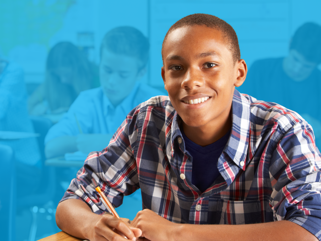 Middle school student smiling at desk during classroom writing activity
