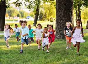 Group of diverse young children running and playing together in a sunny park